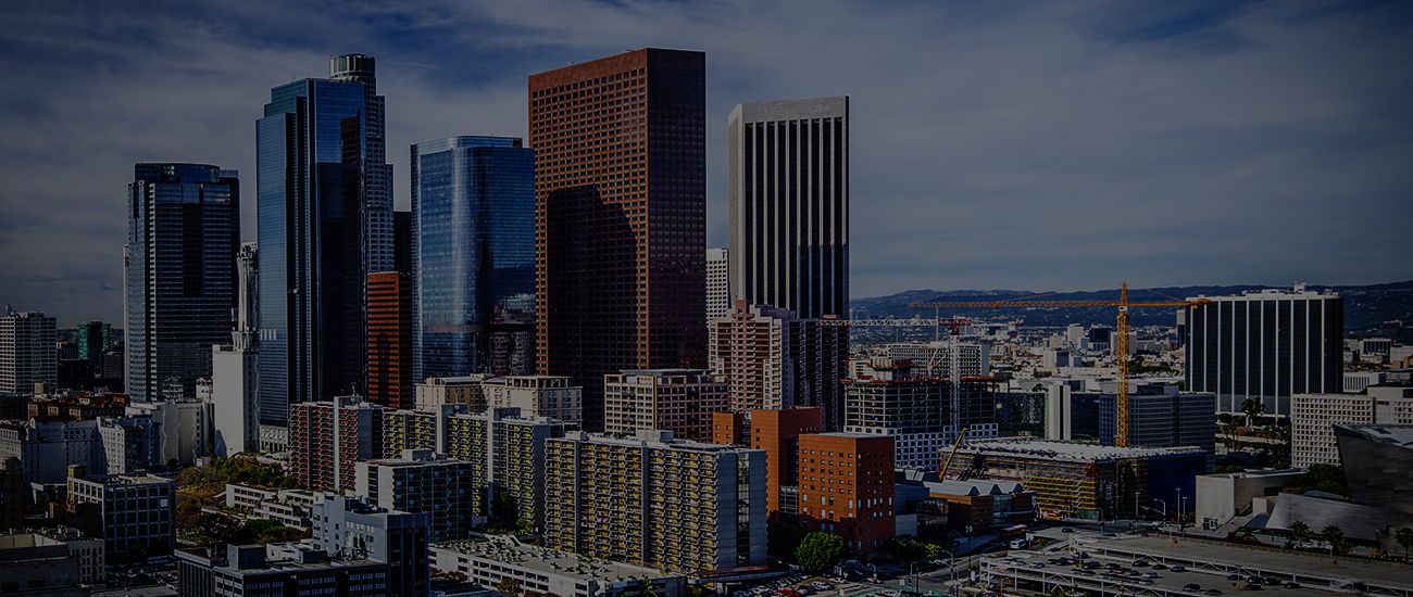 A city skyline featuring modern high-rise buildings against a partly cloudy sky.